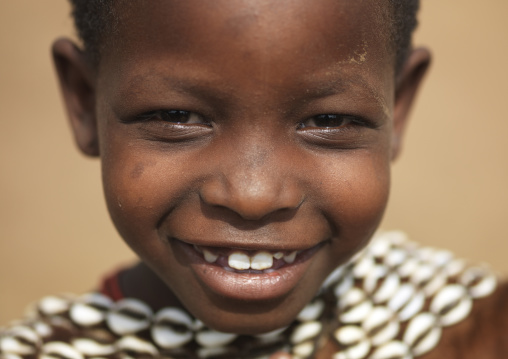 Portrait of beautiful smiling young tsemay girl with a cowry shell collar, Omo valley, Ethiopia