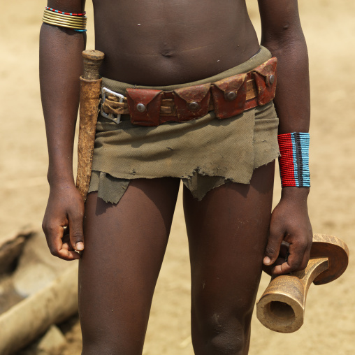 Tsemay woman close up loincloth and belt with a headrest in her hand, Omo valley, Ethiopia