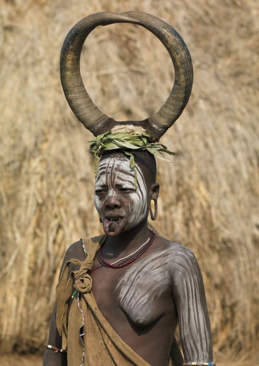 Topless Mursi Woman Portrait Wearing Buffalo Horns On Head And White Paint Ethiopia