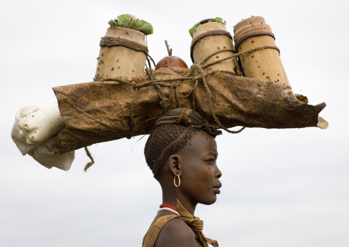 Portrait Of A Bodi Tribe Woman Carrying Butter And Honey In Bamboo Pots On Her Head To Sell At Hana Mursi Market, Omo Valley, Ethiopia