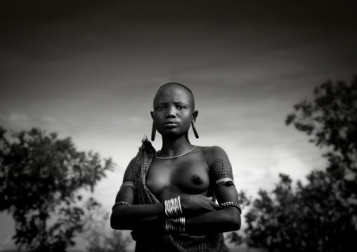 Black And White Portrait Of A Mursi Tribe Woman With Ear Plates And Scarifications, Omo Valley Ethiopia