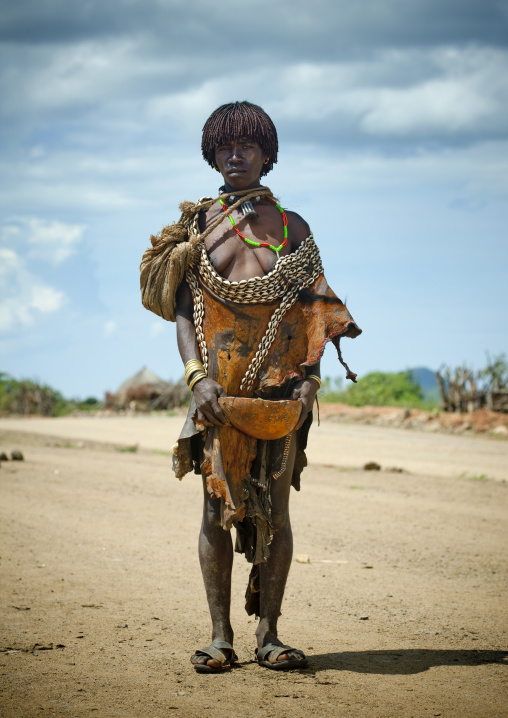 Hamer Tribe Woman Standing And Wearing Shell And Skin Clothing With Half Calabash Container, Omo Valley, Ethiopia
