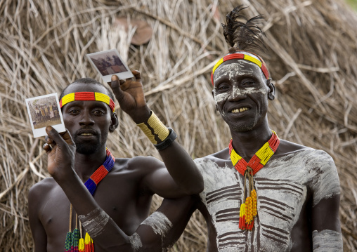 Karo Tribe Men With Body Paintings Showing Polaroids Of The Tribe, Korcho, Ethiopia