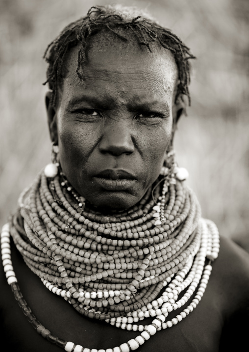 Portrait Of A Senior Nyangatom Tribe Woman Wearing Big Beaded Necklaces And With A Serious Look, Omo Valley, Ethiopia