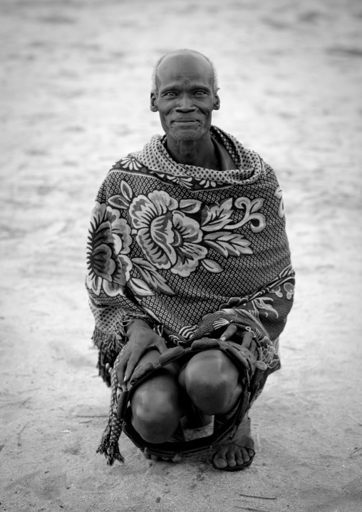 Black And White Portrait Of A Karo Tribe Man Wrapped Up In A Cover And Squatting, Korcho Village, Omo Valley, Ethiopia