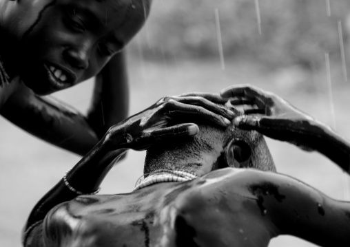 Black And White Picture Of Kids From Karo Tribe Having A Shower Under The Rain, Korcho Village, Omo Valley, Ethiopia