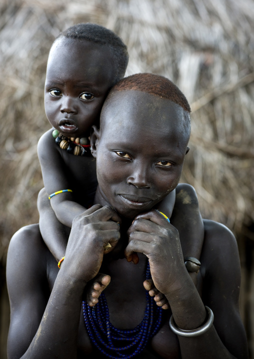 Portrait Of A Karo Tribe Mother Carrying Her Kid On Her Shoulders, Korcho Village, Omo Valley, Ethiopia