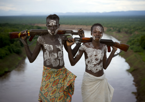 Karo Tribe Boys With Body Paint And Kalachnikovs Posing Over The Omo River, Korcho Village, Omo Valley, Ethiopia