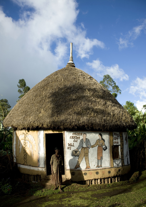Woman standing outside a traditionally painted hosanna house, Ethiopia