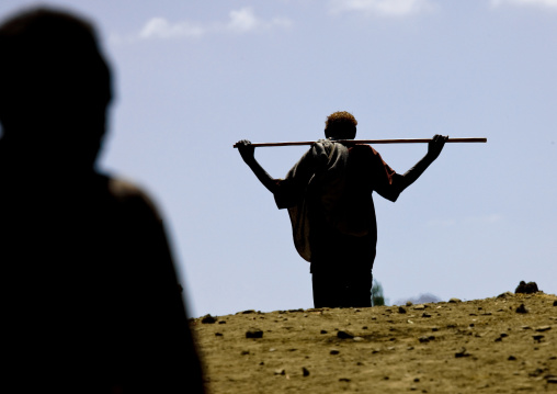 Afar man walking with stick on the shoulders, Bati, Amhara region, Ethiopia
