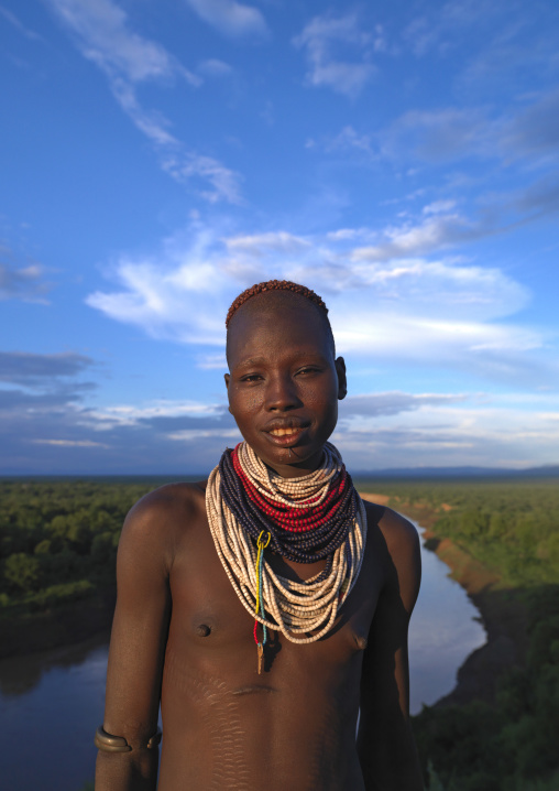 Portrait Of A Young Karo Tribe Woman With Colourful Necklaces Over The Omo River At Sunset, Korcho Village, Ethiopia