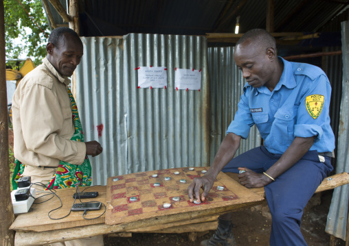 Policeman And Man From Koka Malaysian Plantation Playing Checkers, Omo Valley, Ethiopia