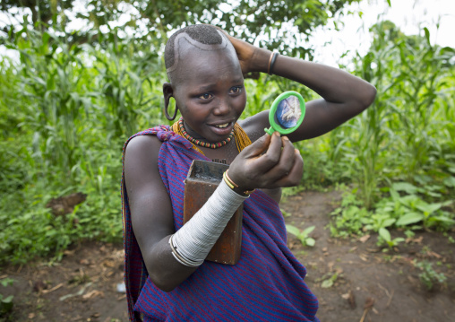 Suri tribe girl looking at her hair, Kibish, Omo valley, Ethiopia