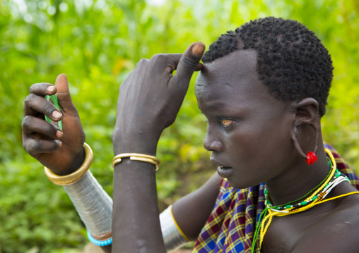 Suri tribe woman looking at her hair, Kibish, Omo valley,  Ethiopia