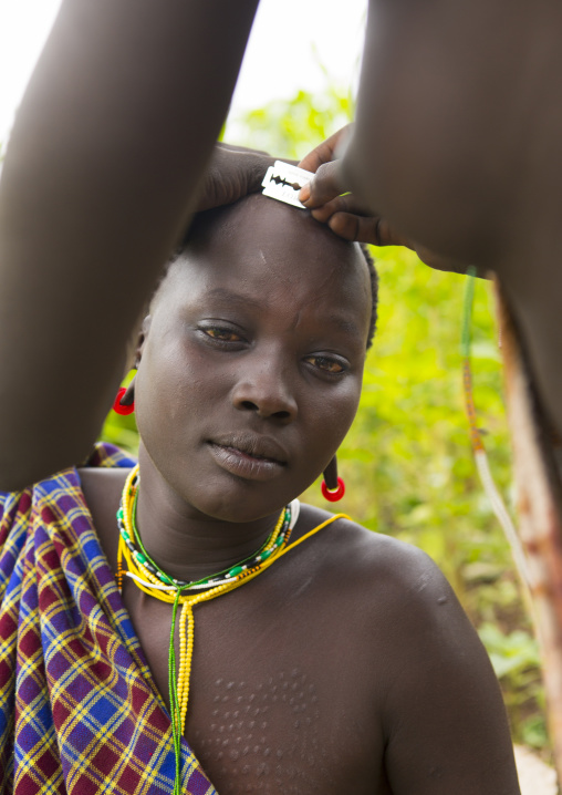 Suri tribe woman having a haircut, Kibish, Omo valley, Ethiopia