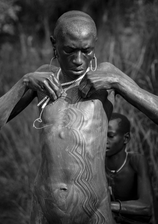 Shepherd From Suri Tribe Receiving Help To Decorate His Body With Camouflage Paintings Before Leaving The Village, Tulgit, Omo Valley, Ethiopia