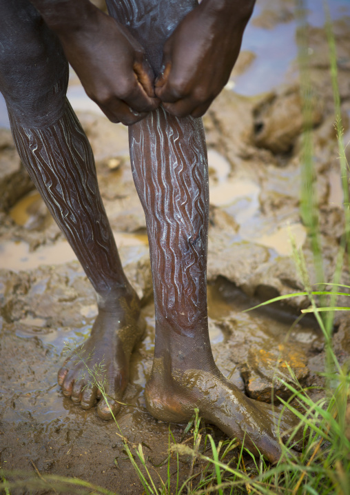 Shepherd from Suri tribe decorating his body with camouflage paintings, Tulgit, Omo valley, Ethiopia