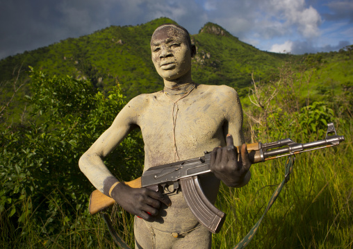 Suri tribe man with body paintings posing with a kalashnikov, Omo valley, Ethiopia