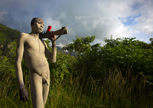 Suri tribe man with body paintings posing with a kalashnikov, Omo valley, Ethiopia