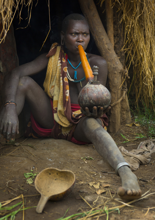 Young Suri woman smoking a pipe, Tulgit, Omo valley, Ethiopia