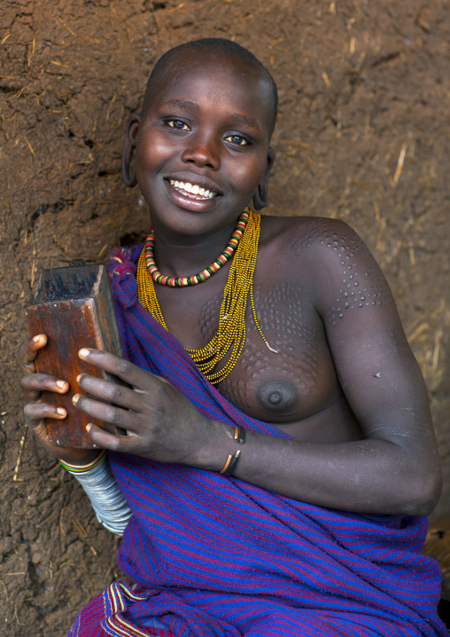 Smiling Suri tribe woman holding a kalimba, Kibish, Omo valley, Ethiopia