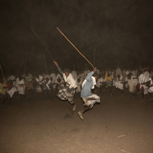 Night Shot Of Two Karrayyu Tribe Men Jumping During A Choreographed Stick Fighting Dance At Gadaaa Ceremony, Metahara, Ethiopia