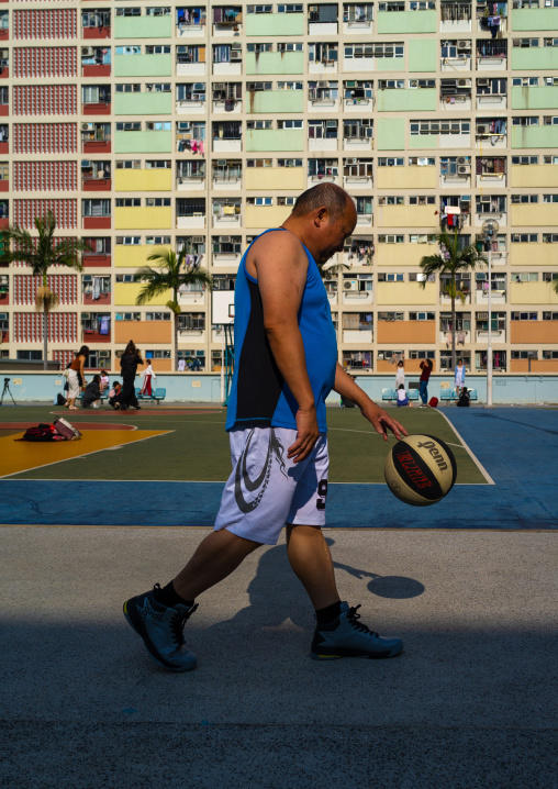 Chinese man playing basket ball in Choi Hung rainbow building, Kowloon, Hong Kong, China