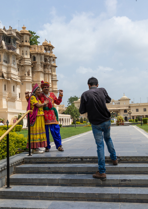 Indian tourists posing in traditional clothing in front of the facade of the city palace, Rajasthan, Udaipur, India