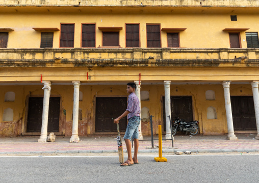 Young boy holding a cricket bat and playing in the street, Rajasthan, Jaipur, India