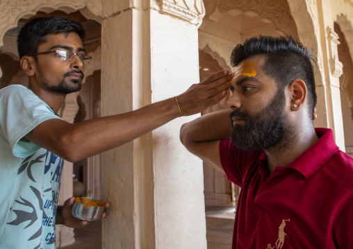 Indian man making a tika on the forehead of his friend in shiva temple, Rajasthan, Jaisalmer, India
