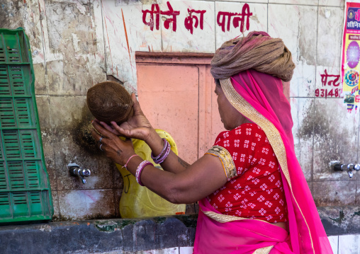 Indian woman collecting water in the street during ther heat wave, Rajasthan, Jaipur, India