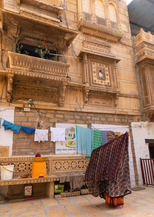 Indian woman hanging saris in front of her haveli, Rajasthan, Jaisalmer, India