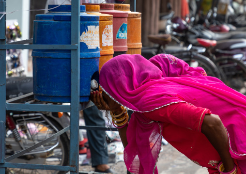 Rajasthani women drinking water in the street during the heat wave, Rajasthan, Bikaner, India