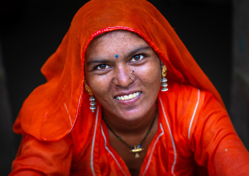 Portrait of a smiling rajasthani woman in traditional orange sari, Rajasthan, Jaisalmer, India