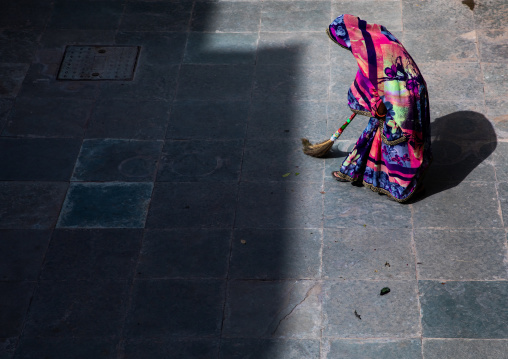 Indian woman cleaning a courtyard with a broom, Rajasthan, Bundi, India
