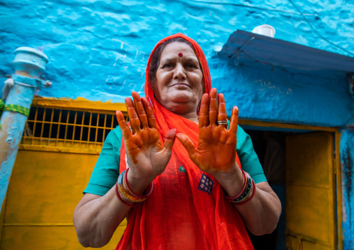 Portrait of a rajasthani woman in traditional sari showing her orange hands with henna, Rajasthan, Jodhpur, India