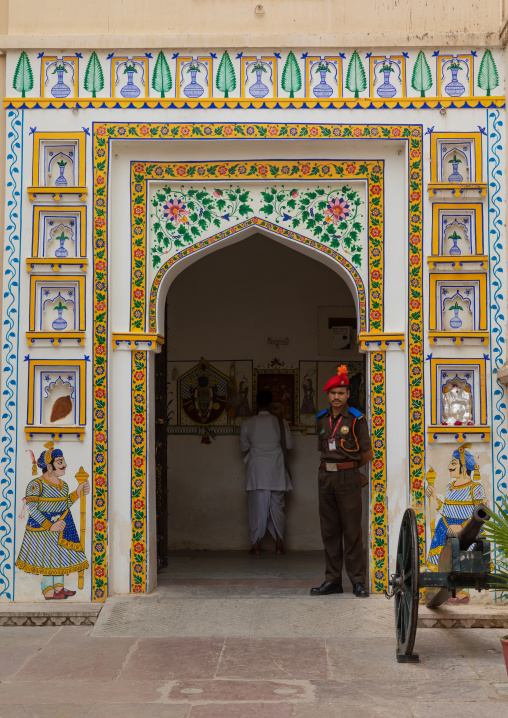 Indian guard in front of an old door in the city palace, Rajasthan, Udaipur, India