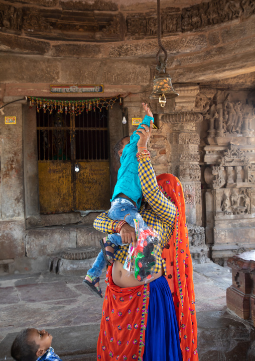 Indian mother helping her son to ring the bell in Harshat Mata temple, Rajasthan, Abhaneri, India