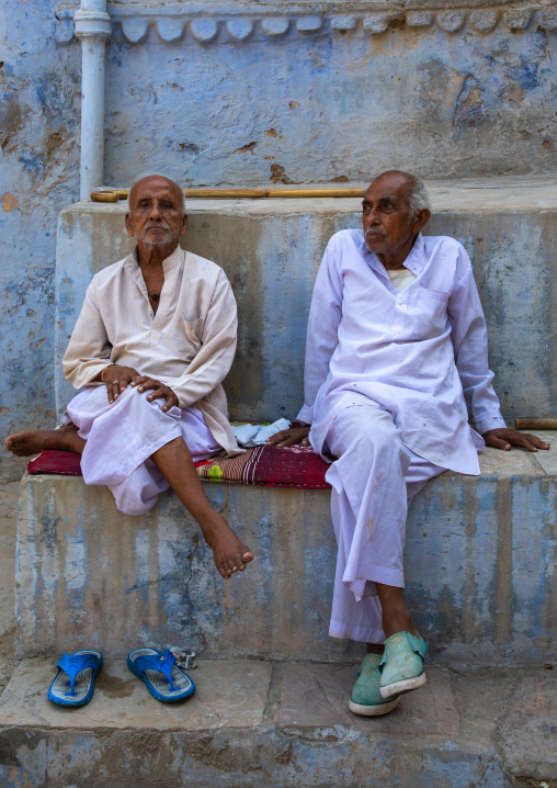Indian men sit in front of an old blue house of a brahmin, Rajasthan, Bundi, India