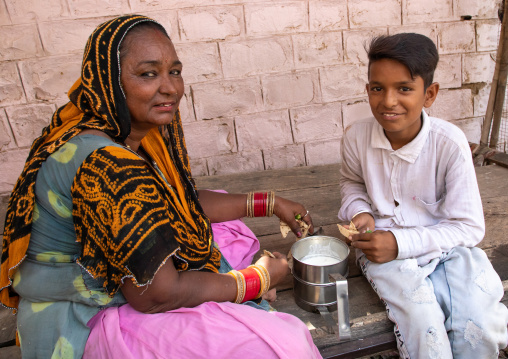 Portrait of rajasthani woman with her son having lunch in the street, Rajasthan, Jaisalmer, India