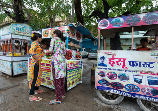 Indian women in front of food stalls selling street food, Rajasthan, Nawalgarh, India