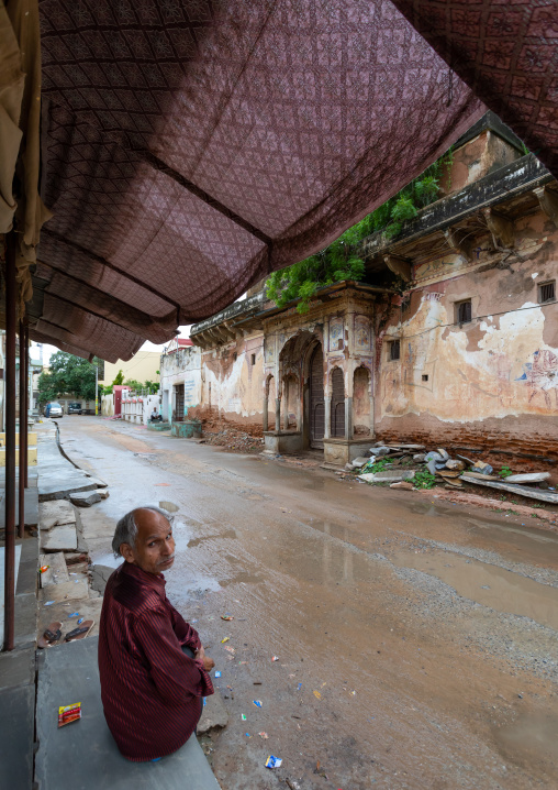 Indian man sit in front of an old historic haveli, Rajasthan, Nawalgarh, India