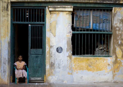 Little Girl Who Is Bored Sitting On A Blue Plastic Chair On The Doorstep Of An Old Colonial House In Chennai, India