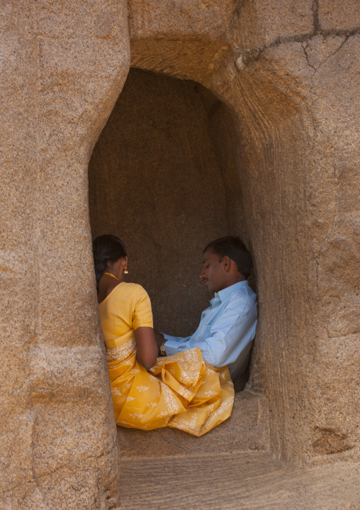 Couple Of Midadult Person Sitting On The Edge Of A Window Cut In Rock, Mahabalipuram, India