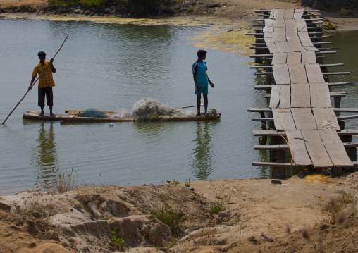 Fishermen On A Small Boat With Their Nets Approaching A Wooden Bridge, Mahabalipuram, India