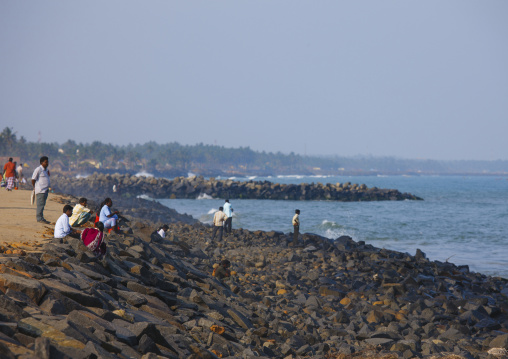 People Sitting On Rocks Of A Seawall At Pondicherry Seafront Looking Toowards The Horizon, India