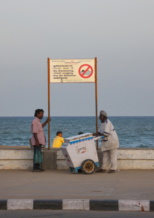 Ice-cream Seller Chatting With An Ohter Man In Front Of A No Swimming Sign At Pondicherry Seaside, India