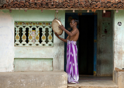 Semi-dressed Man In Front Of His House Hanging A Plate To A Beam, Pondicherry, India