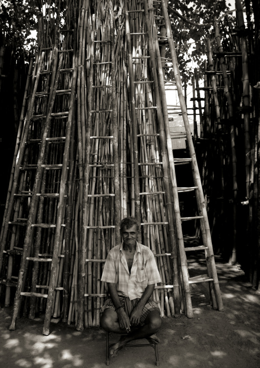 Old Amused Indian Man Sitting In The Shade Of Trees In Front Of Wooden Scales, Madurai, India