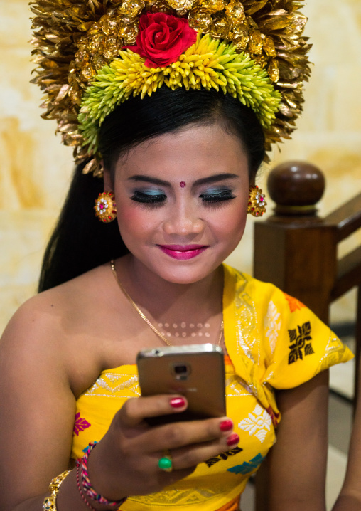 A Teenager Girl In Traditional  Costume Using Her Mobile Phone As A Mirror  Before A Tooth Filing Ceremony